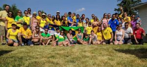 A large group of people involved in the Brazilian community gathered outside, holding the Brazilian flag.