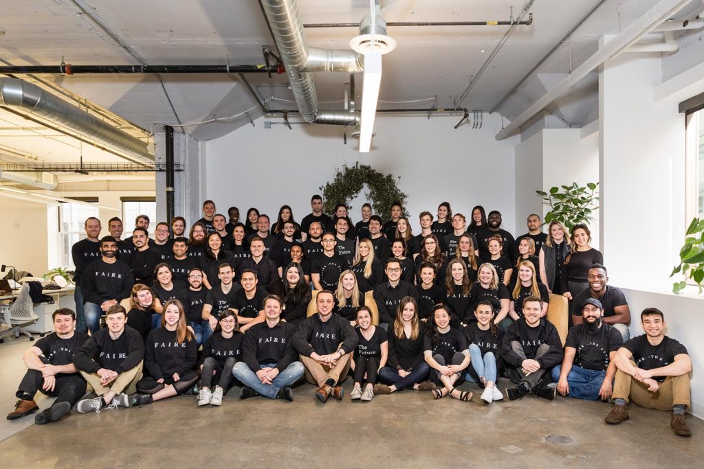 The entire Faire team gathered in their office, decked out in Faire shirts.